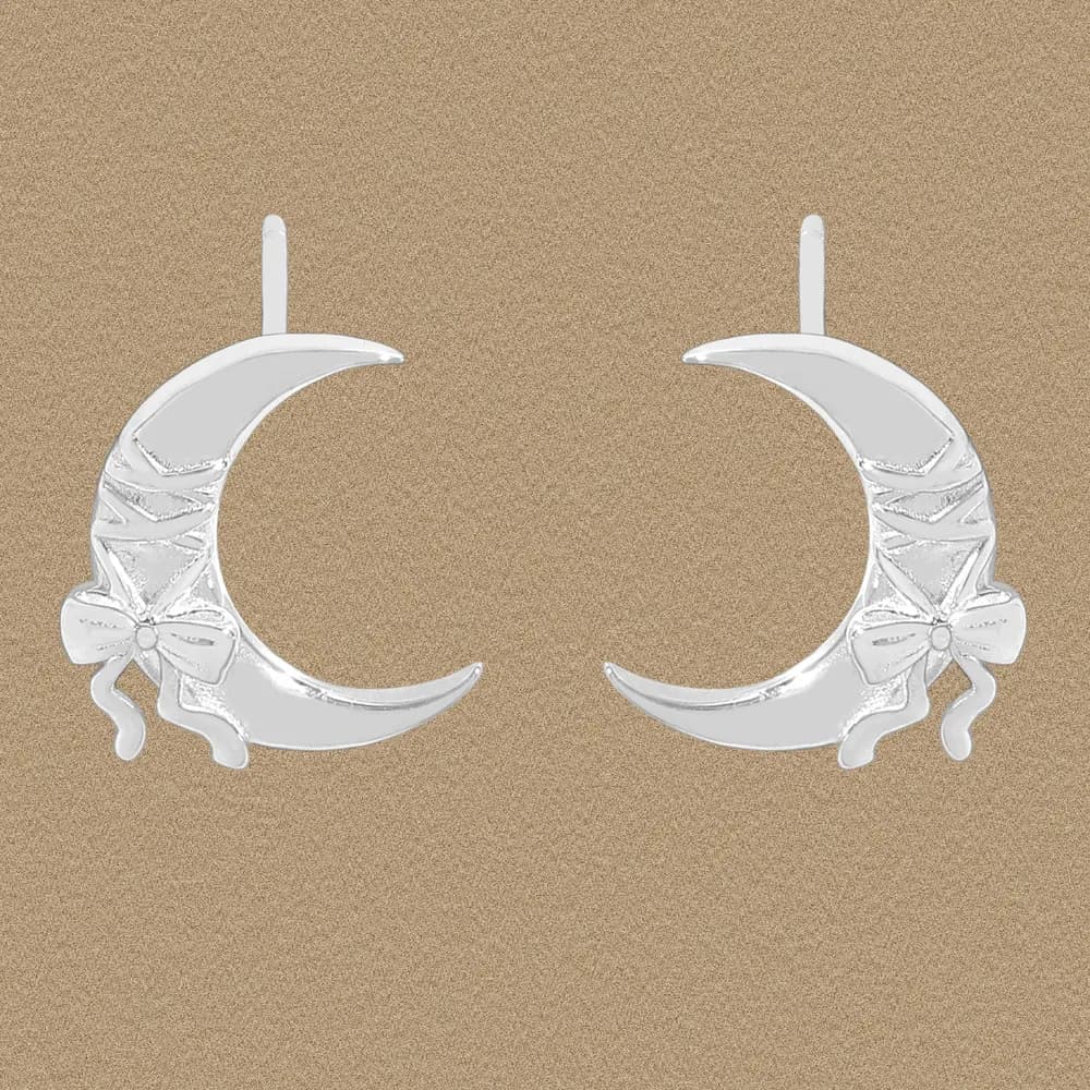 Polished sterling silver crescent moon earrings with a bow detail dangling from posts.