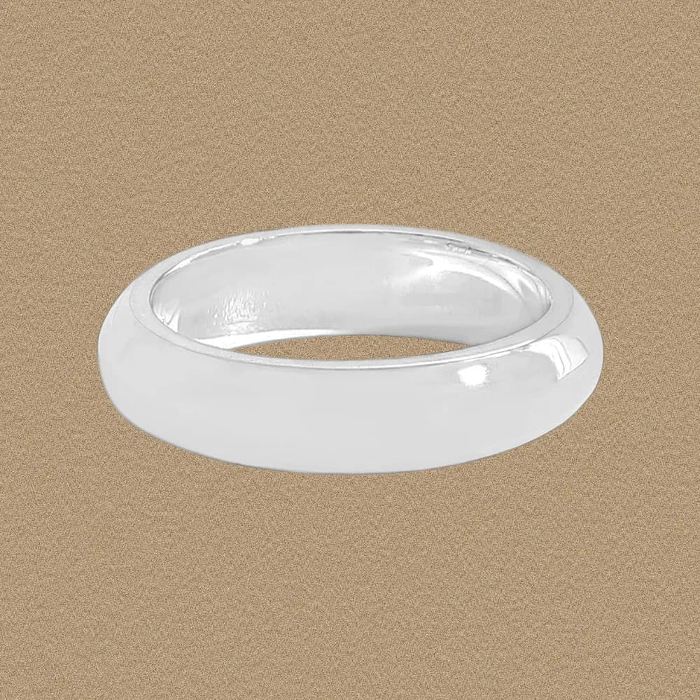 A wide, polished sterling silver ring with a rounded, pillow-like dome from a side-angle view.