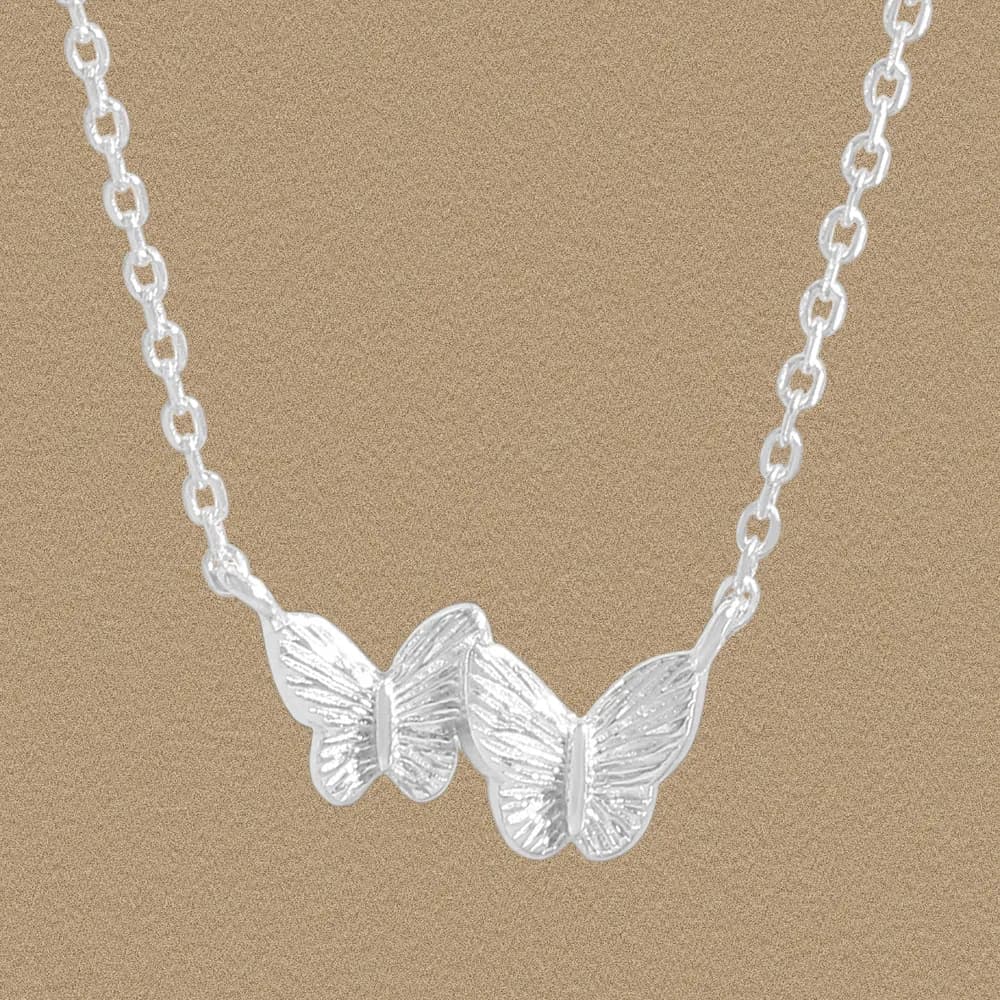 Sterling silver necklace with two textured butterfly pendants forming a double-wing centerpiece on a linked chain.