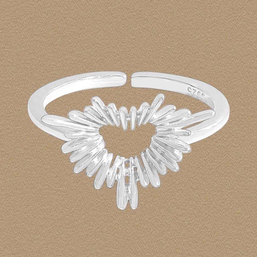 Polished sterling silver ring with a sunburst, heart-shaped negative space at the center and an open band.