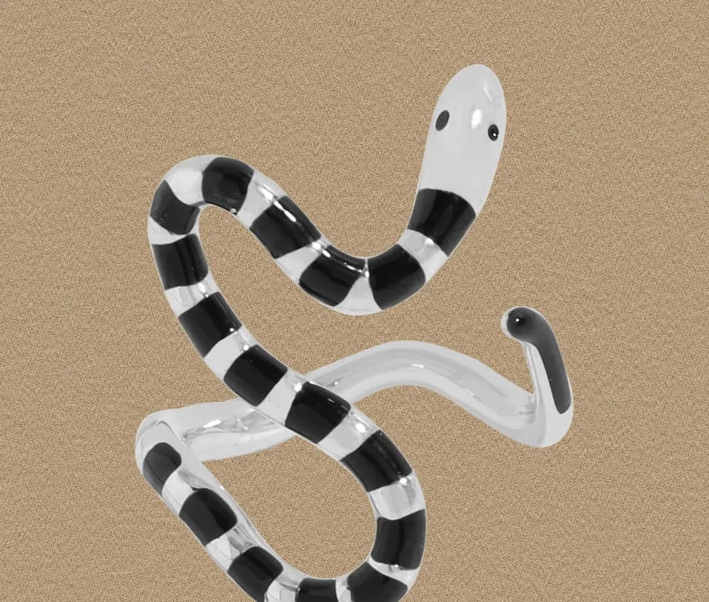 Polished sterling silver striped snake ring with black and white enamel in a double-loop design against a beige background.