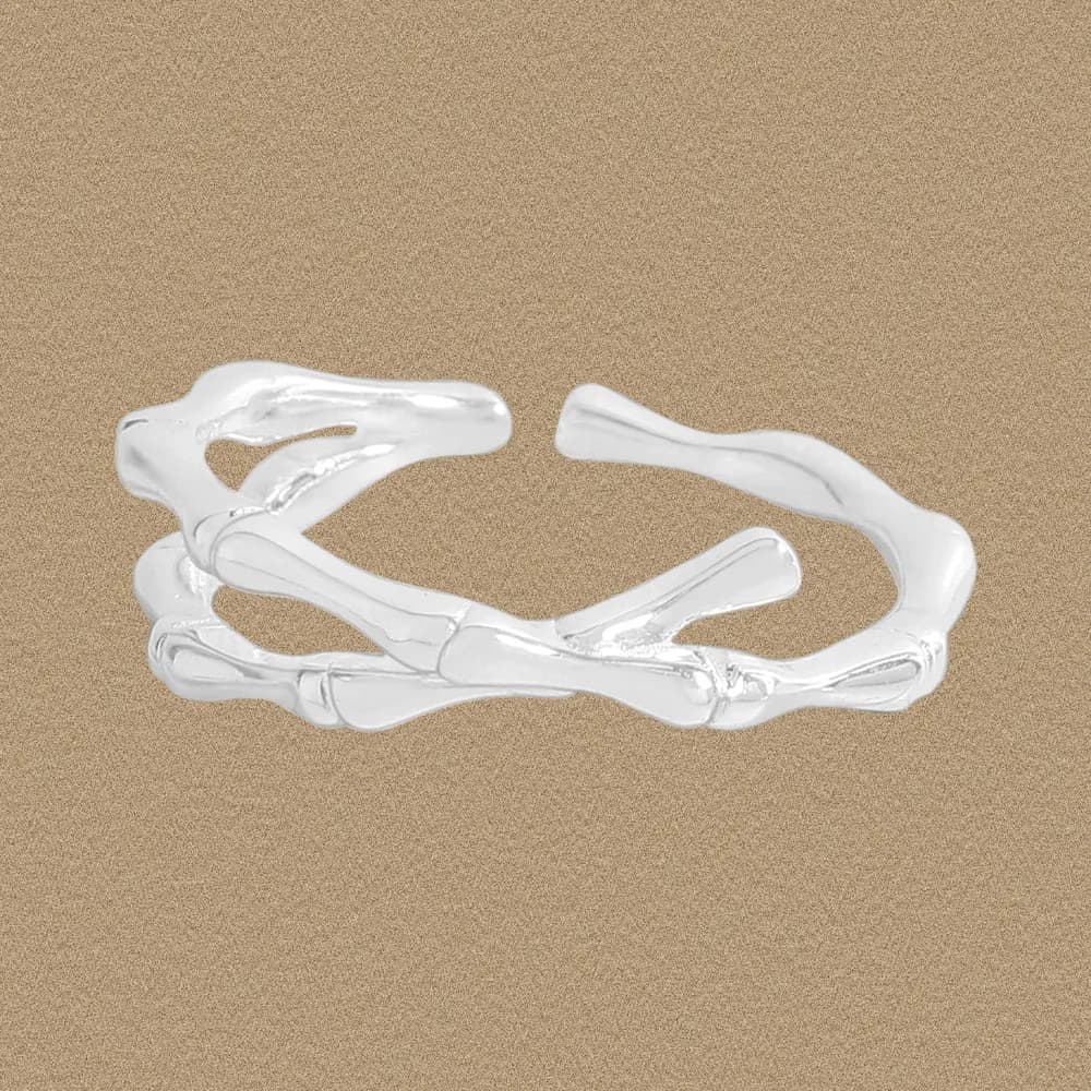Sterling silver twisted branch ring with interwoven bands on a sandy backdrop.