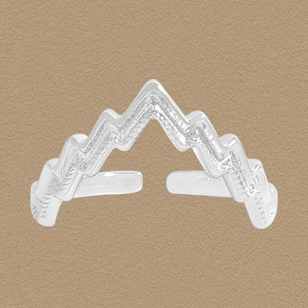 Polished sterling silver mountain-peak chevron ring with an open center on a warm, textured background.