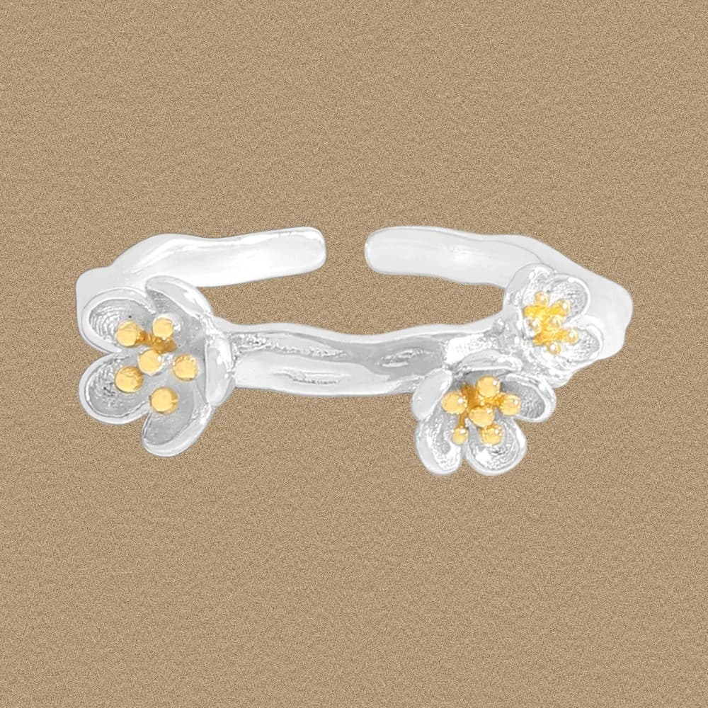 Open sterling silver ring with two floral charms at each end connected by a curved band.