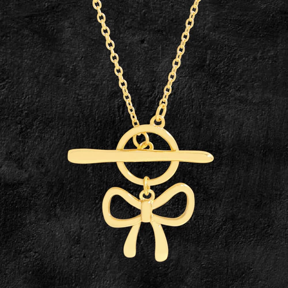 Gold-tone T-bar pendant with a bow charm hanging from a circular ring on a chain.