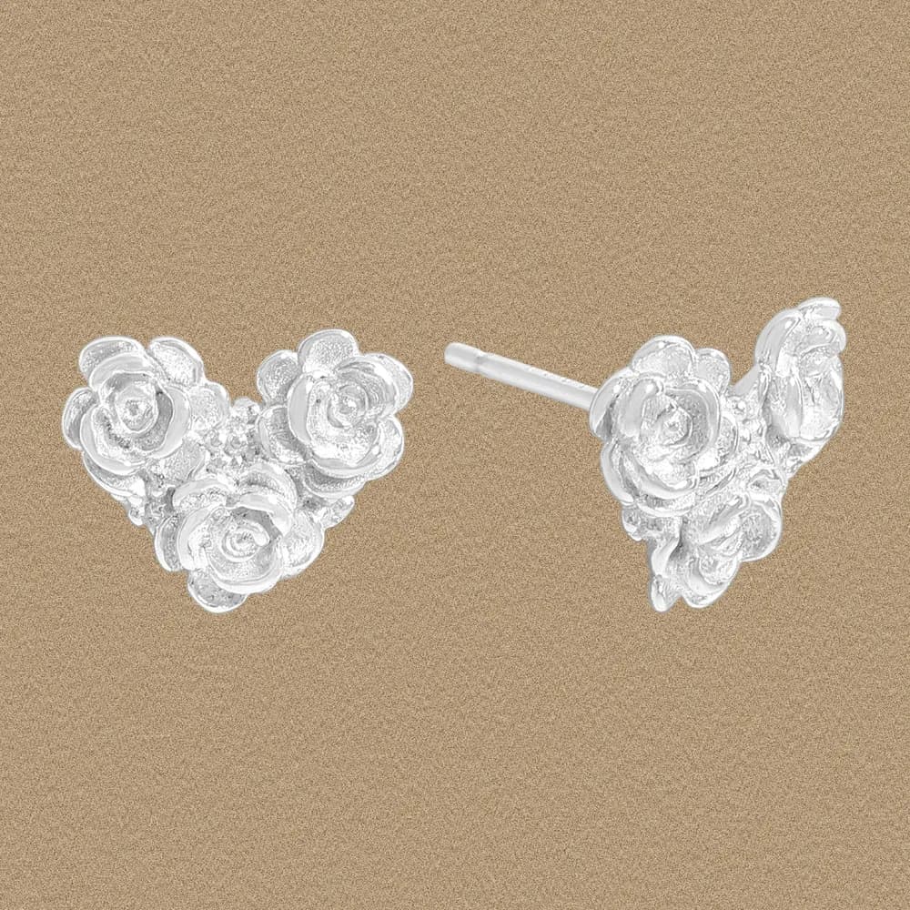 Sterling silver rose cluster stud earrings on a textured tan background.