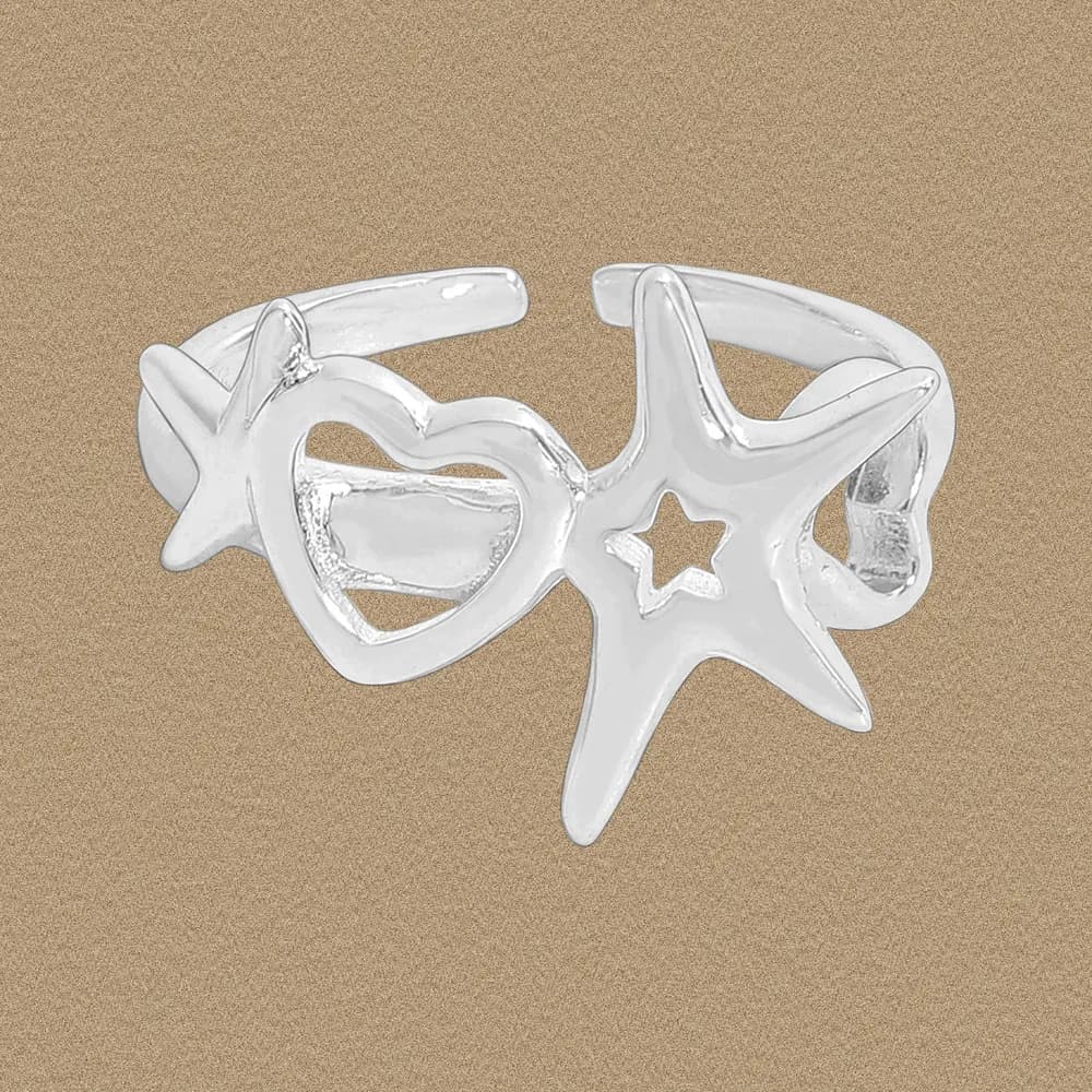Polished sterling silver ring with open heart and star cutouts on a tan background.