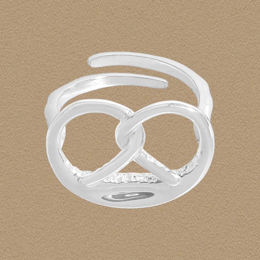 Polished sterling silver ring with an intertwined infinity knot design on a warm background.