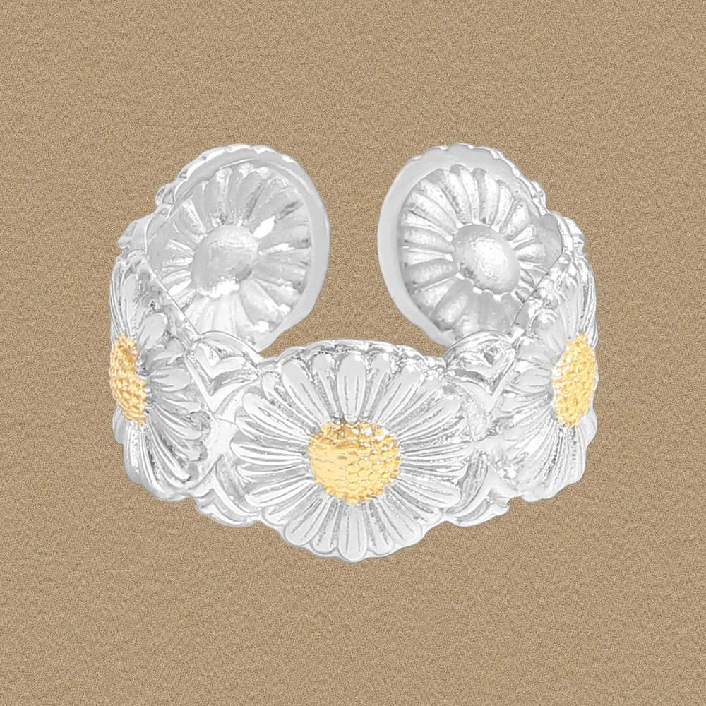 Sterling silver daisy flower ring with gold centers displayed on a beige background.