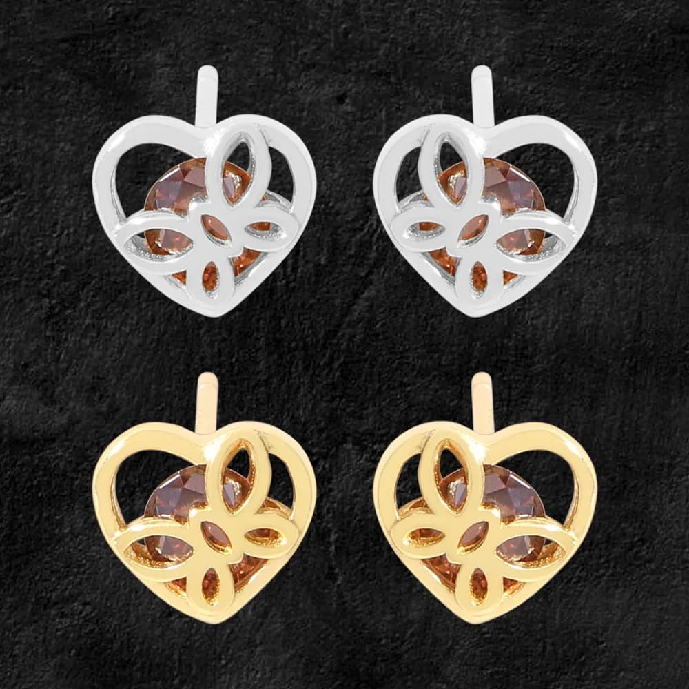 Pair of heart-shaped stud earrings with an intricate openwork filigree design surrounding a brown gemstone.