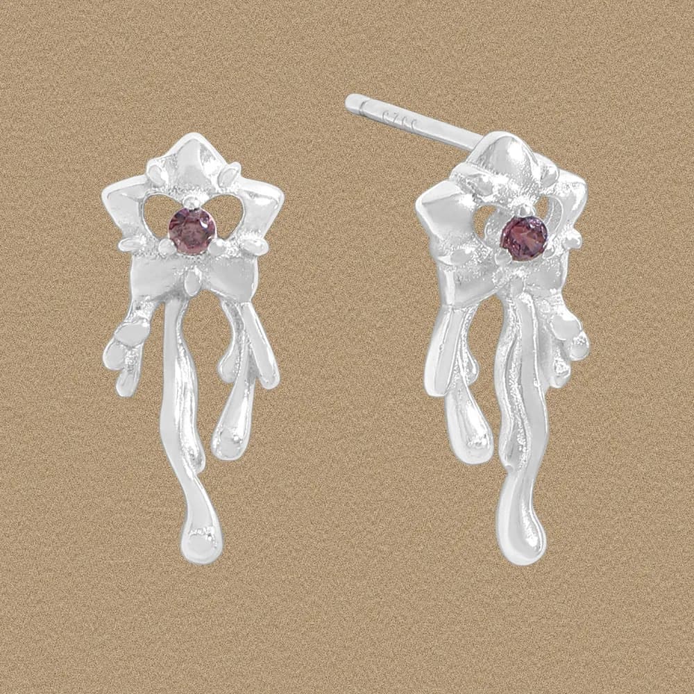 Polished sterling silver bow-shaped earrings with a central purple gemstone and hanging ribbon-like drips.