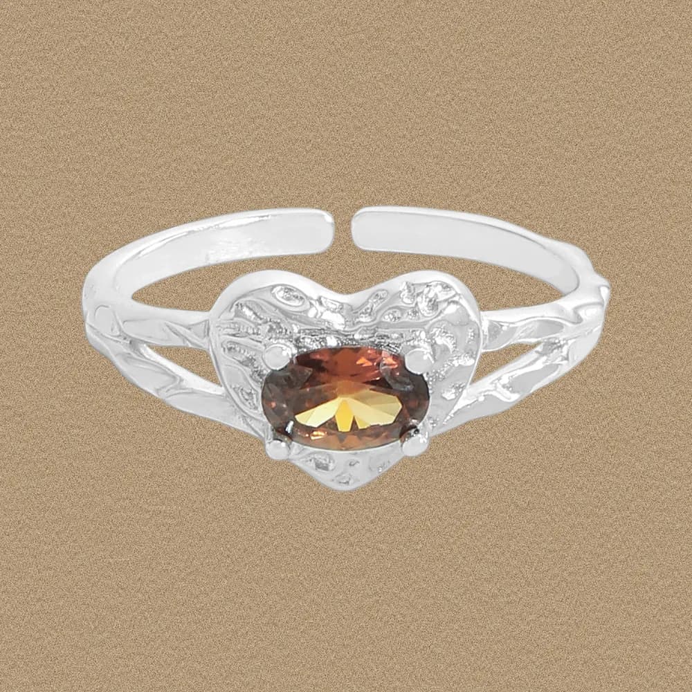 Sterling silver ring with a heart-shaped engraved centerpiece and an oval amber-toned gemstone