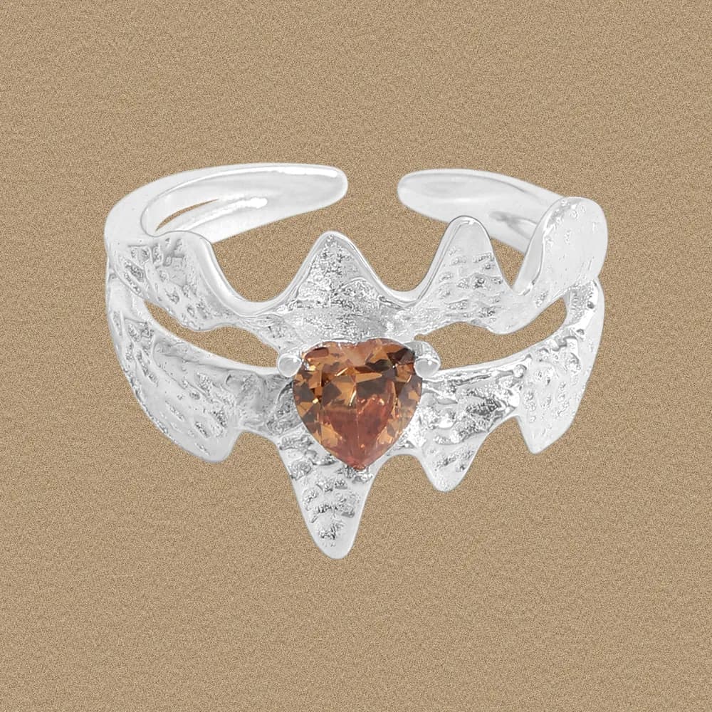 Polished sterling silver ring with a jagged, wavy band and a pear-cut orange gemstone at the center