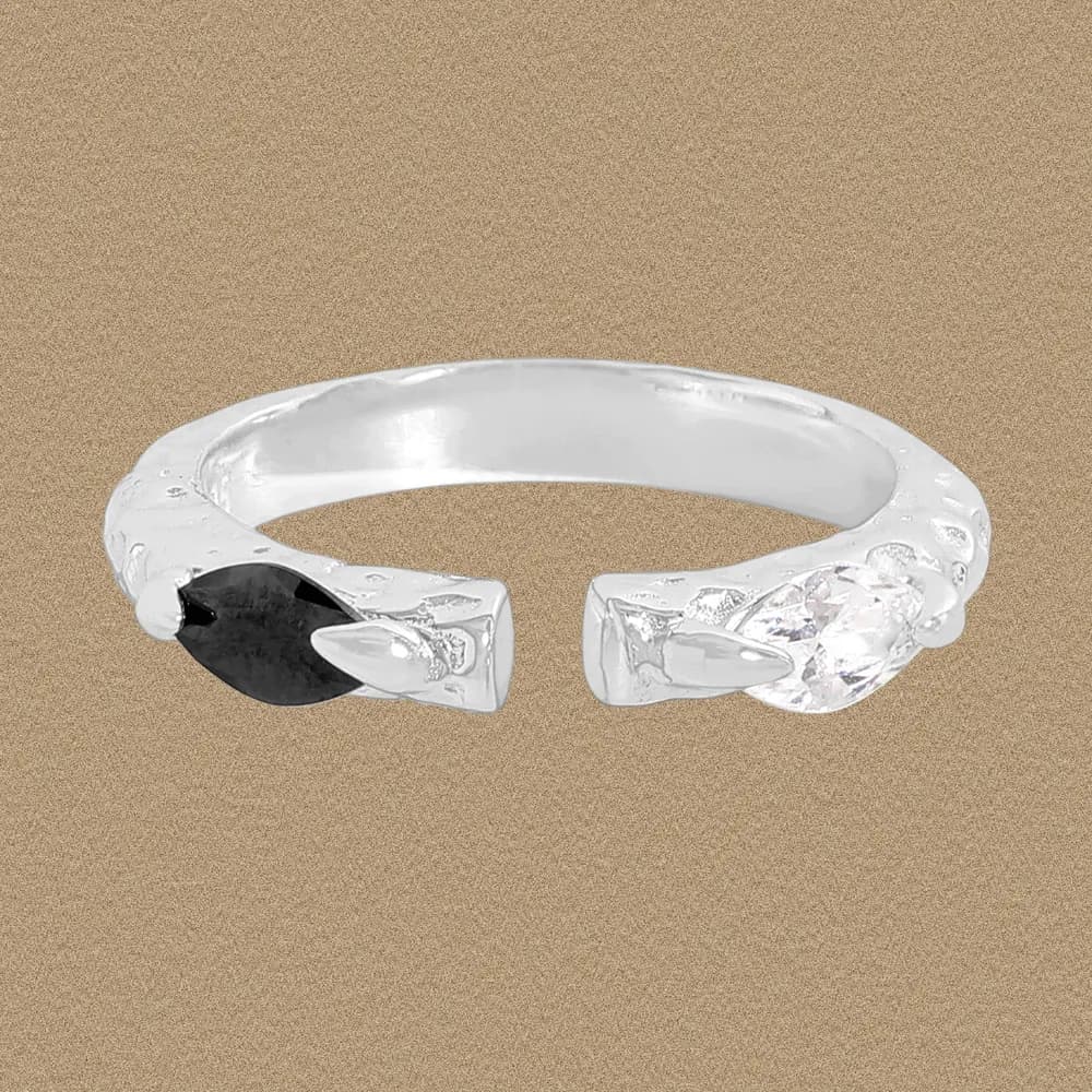 Open-ended sterling silver ring with black marquise and clear stone ends, displayed on a warm background.
