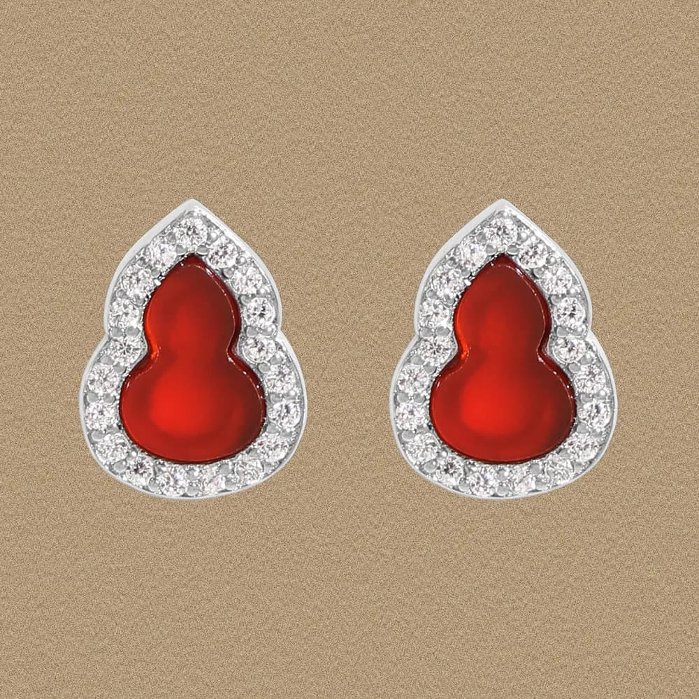 Pair of sterling silver stud earrings with red teardrop cabochons surrounded by a diamond halo.