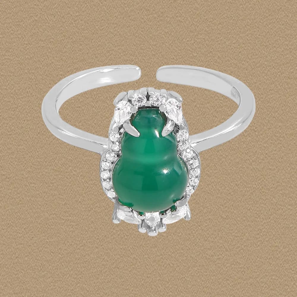 Silver ring with a green jade centerpiece surrounded by a diamond halo on a simple polished band.