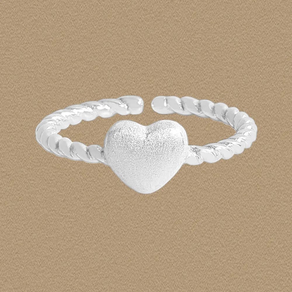 Sterling silver ring with a textured heart centerpiece and twisted rope band photographed against a beige background.