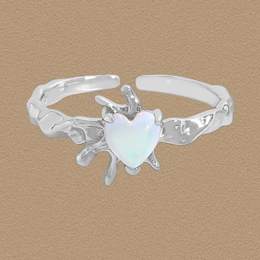 Close-up of a polished sterling silver ring with a heart-shaped opal centerpiece and an irregular, sea-worn band.