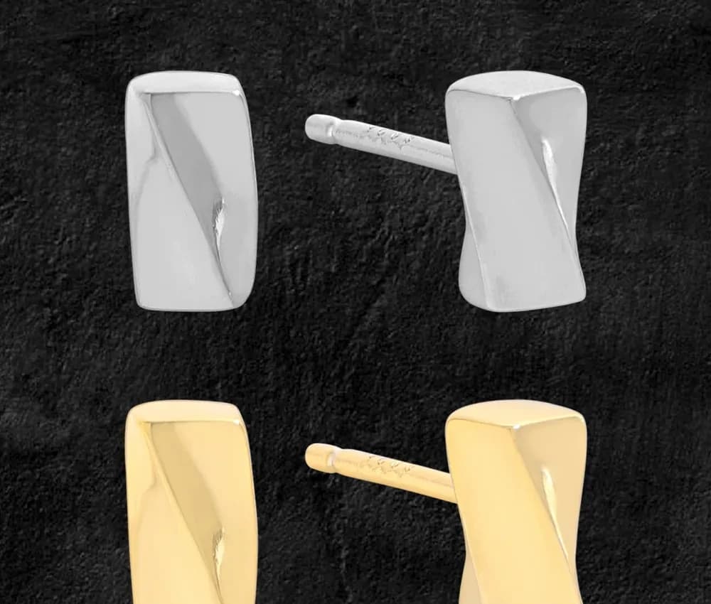 Polished rectangular bar stud earrings in silver and gold-tone finishes mounted on a dark background.