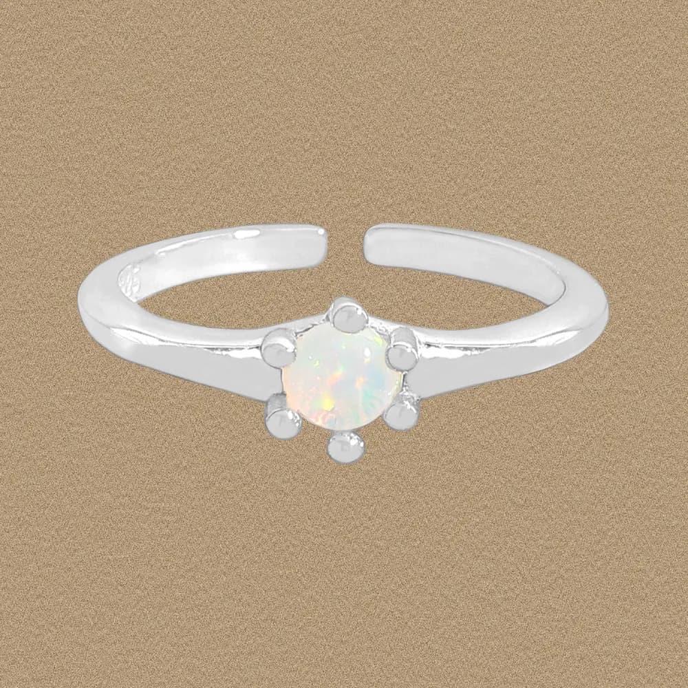 Polished sterling silver ring with a round opal center and bead halo on a neutral background.