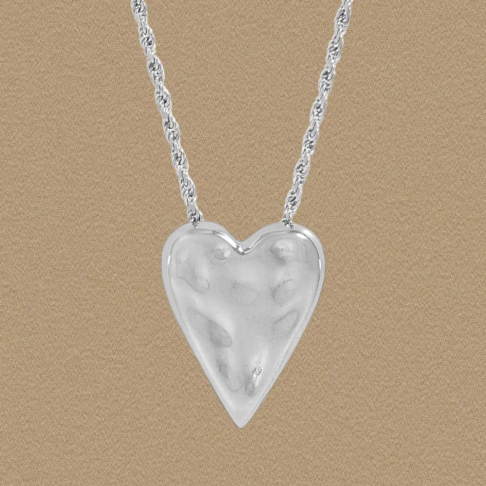 Polished sterling silver heart pendant on a twisted rope chain necklace against a neutral background.