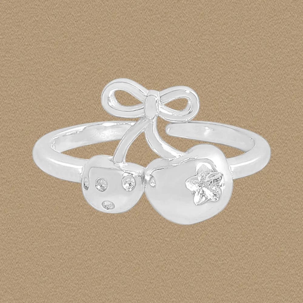 Polished silver Bow Charm Ring with two disk charms and a small bow sits on a tan background.