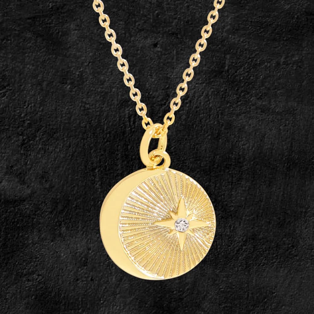 Polished sterling silver sunburst pendant with a star and central crystal on a chain against a dark background.