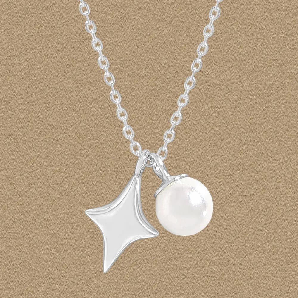 Polished sterling silver necklace with a curved star charm and a pearl ball pendant on a fine chain.
