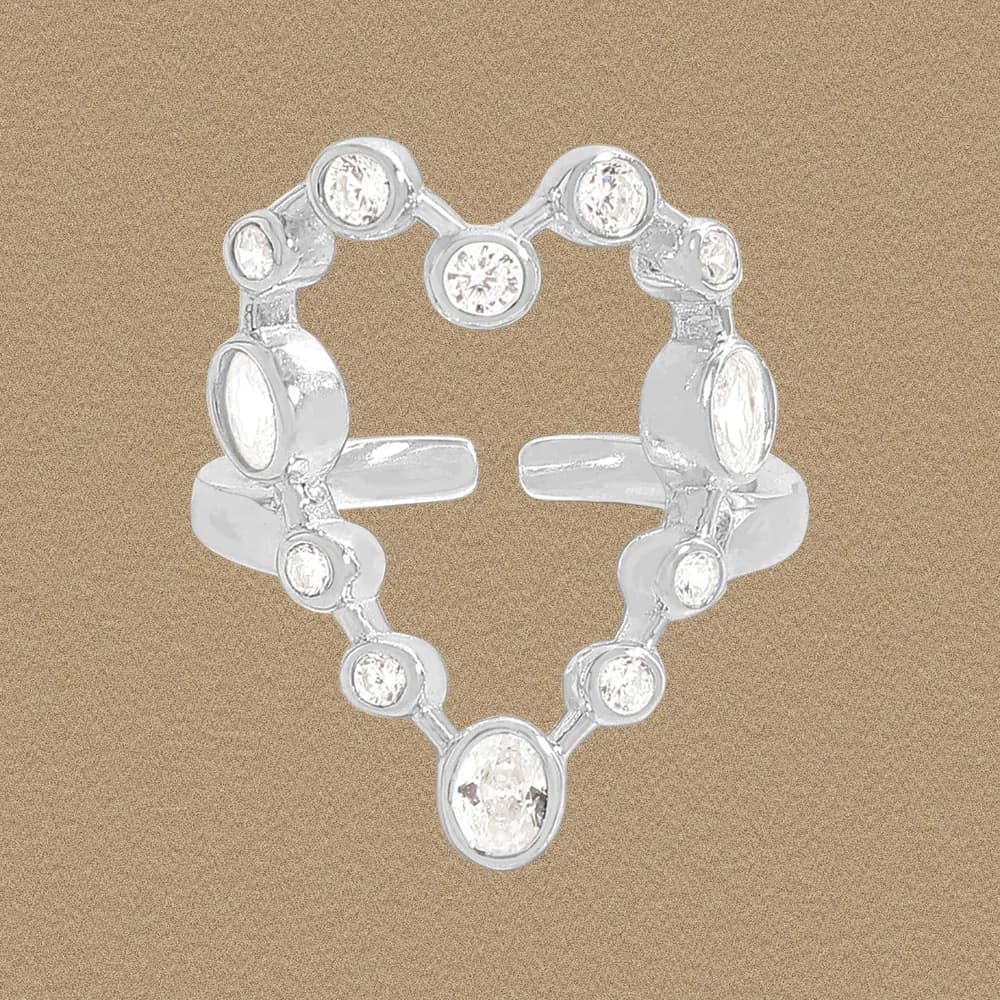 Polished sterling silver ring shaped as a hollow heart with bezel-set stones on a warm background.