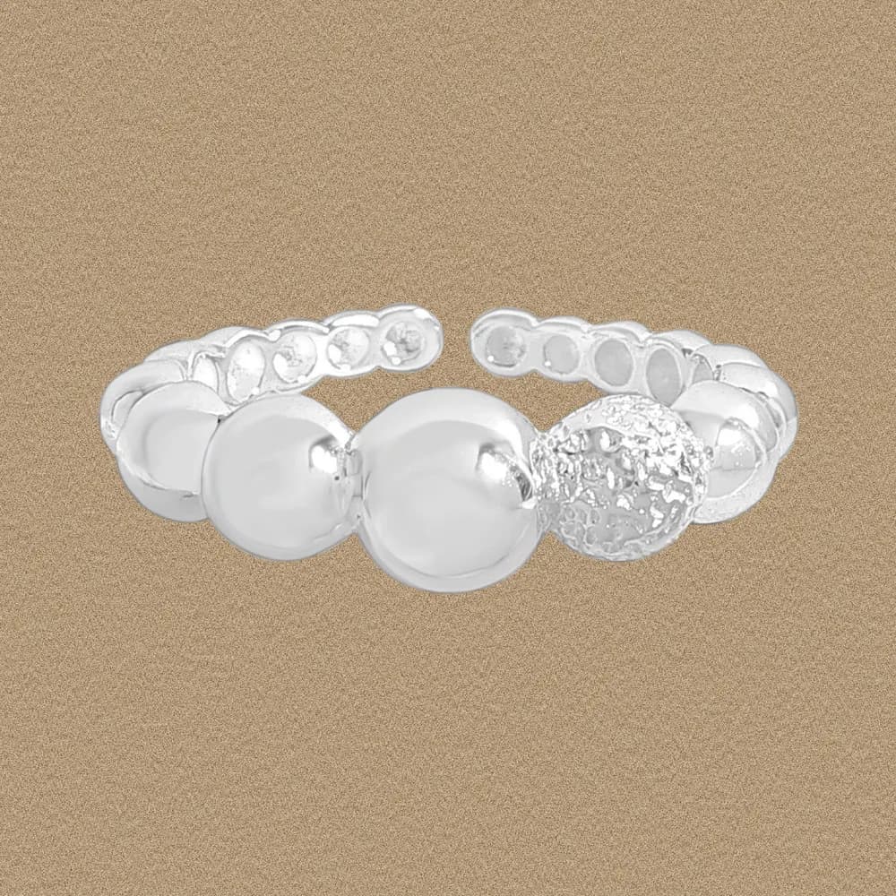 Polished sterling silver beaded ring with a textured accent bead shown against a warm beige background.