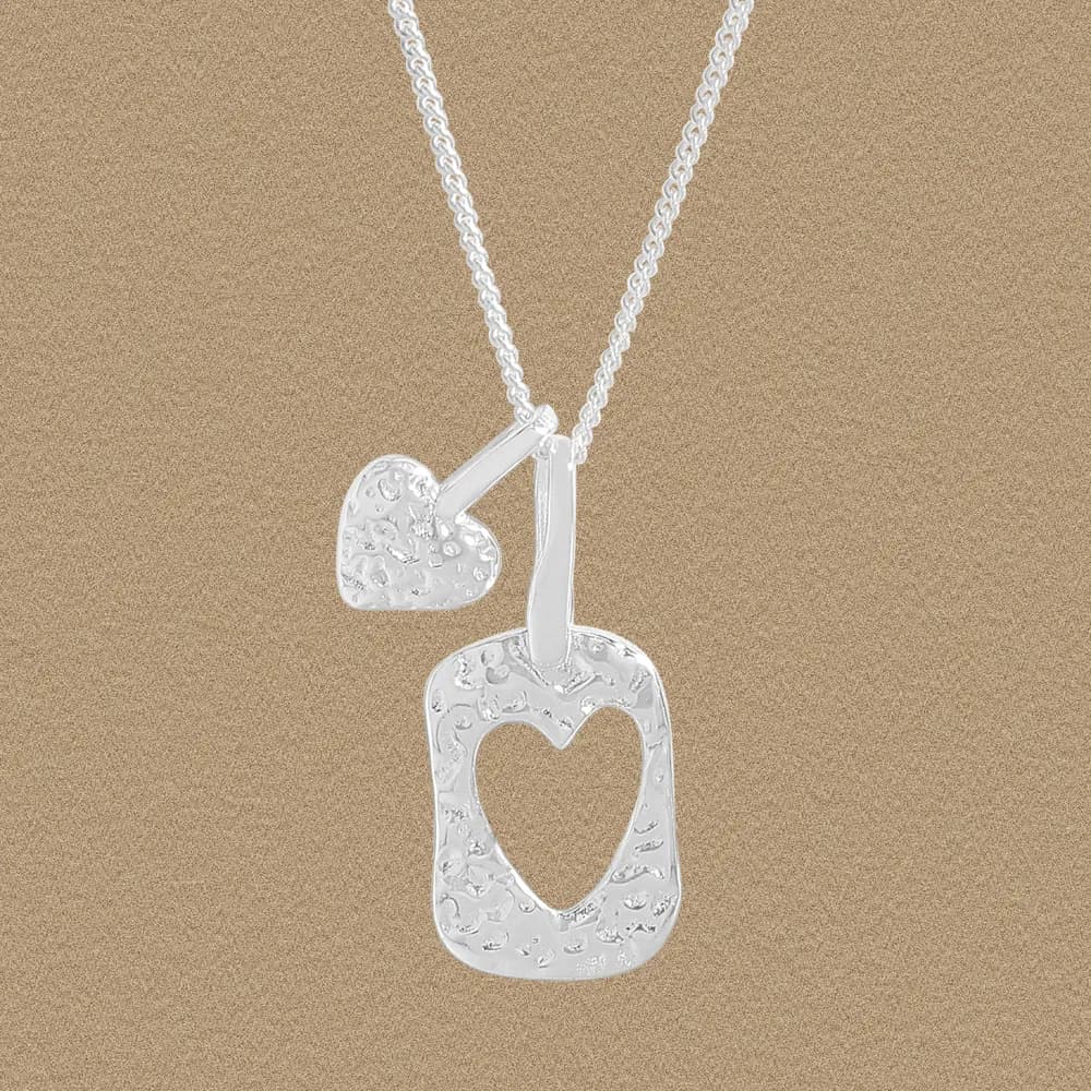 Sterling silver necklace with a textured hollow heart pendant and a small solid heart charm.