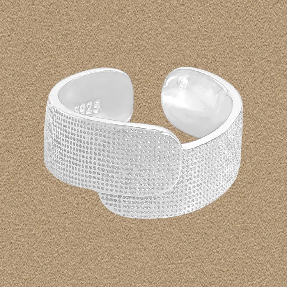 Open-ended sterling silver band ring with a dotted texture on a neutral background.