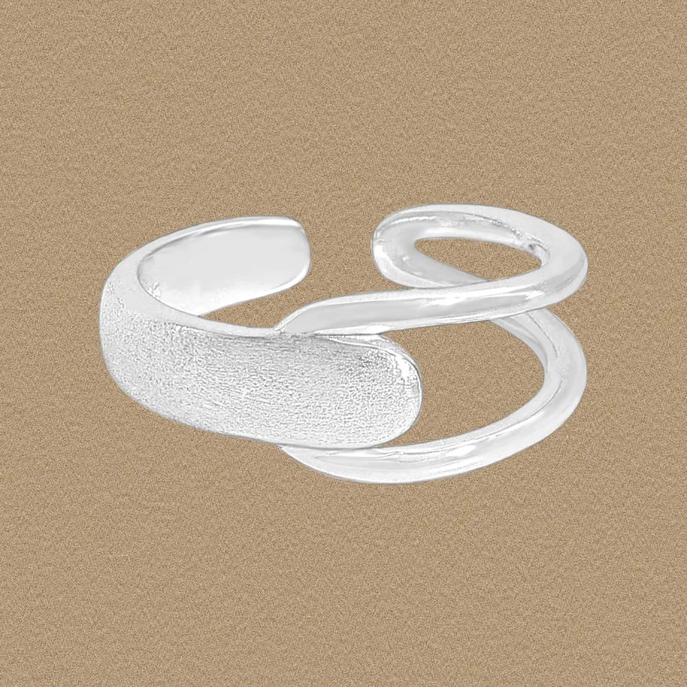 A sterling silver open double-loop ring with one textured end and one smooth end against a beige background.