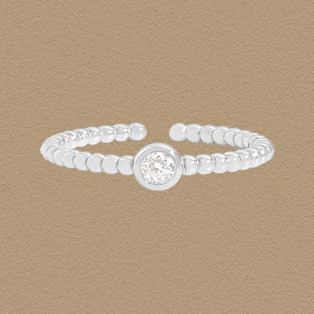 Sterling silver beaded band ring with a central bezel-set stone on a warm background.