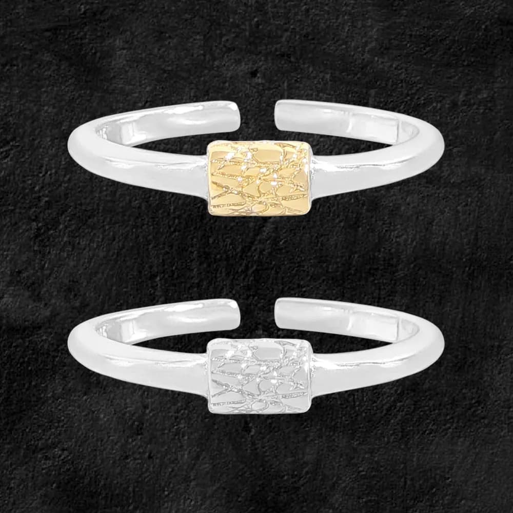 Two-tone open-band ring with textured gold-tone cylinder centerpiece on a dark background.