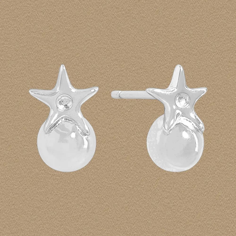 Polished sterling silver star earrings with a clear central gem and a spherical drop, shown against a warm beige background.