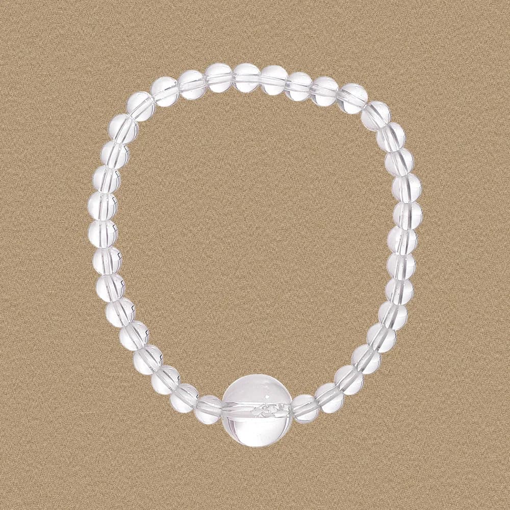 Clear crystal bead bracelet displayed on a warm textured background