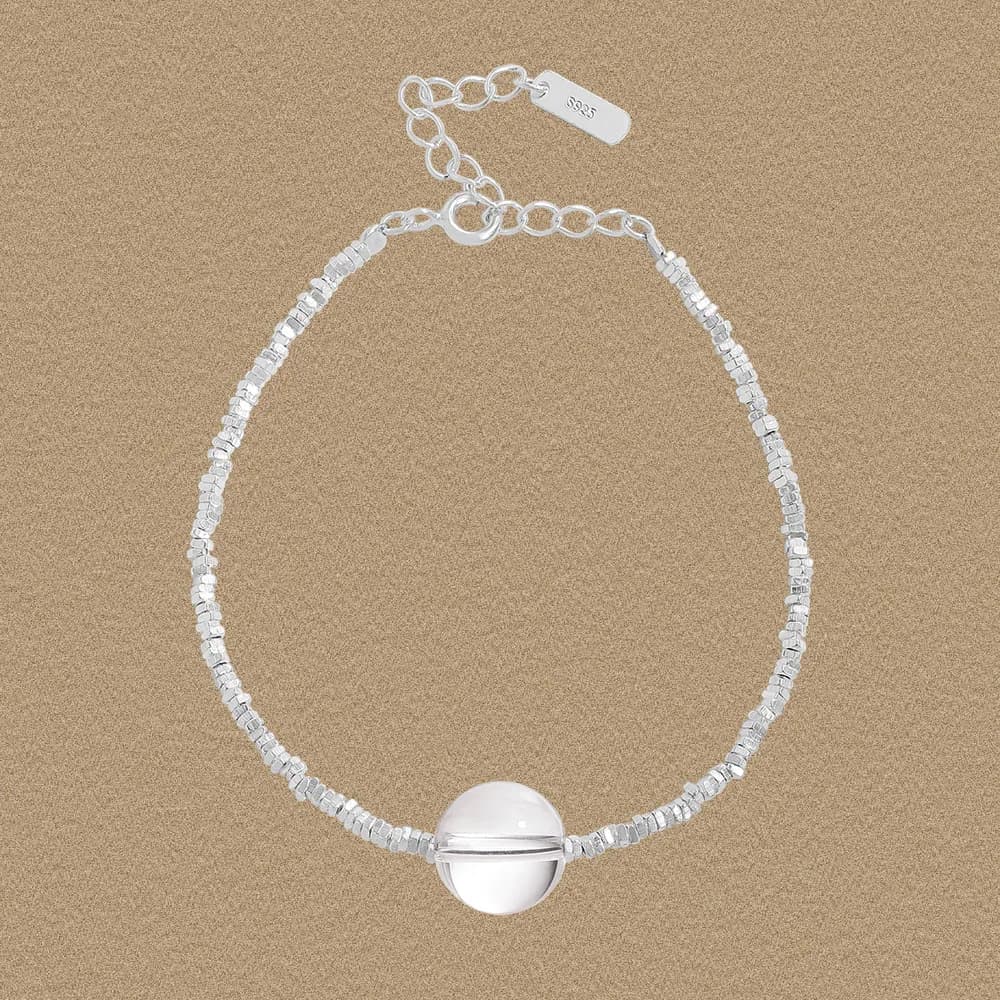 Sterling silver beaded bracelet with a round sphere centerpiece on a beige background.