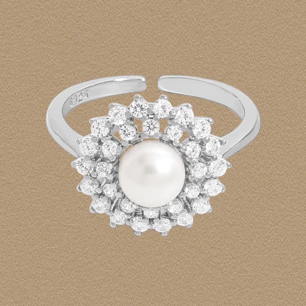 Sterling silver ring with a central pearl surrounded by a halo of small crystals in a floral cluster.