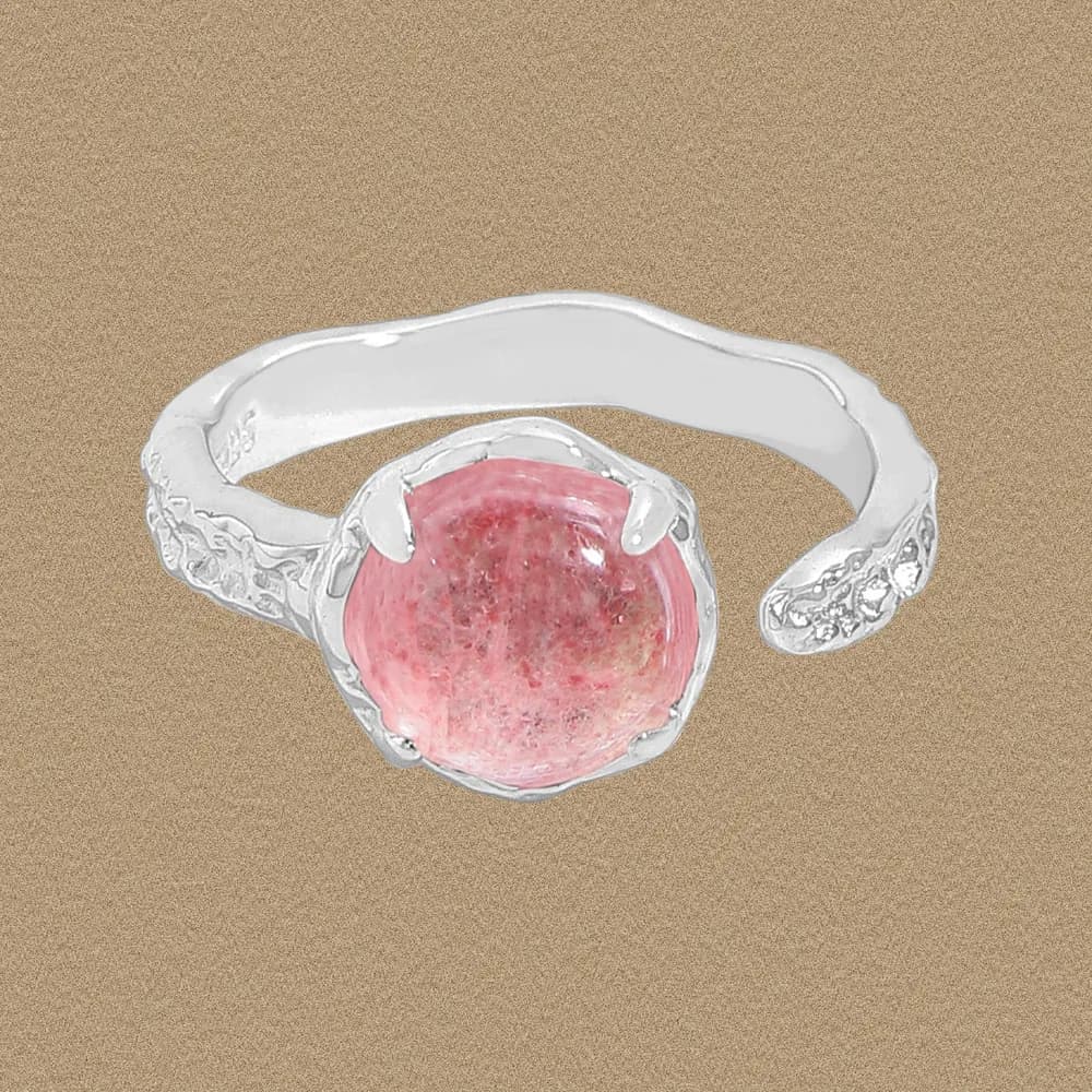 Sterling silver ring with a round pink cabochon in a prong setting and a textured, sculpted band.
