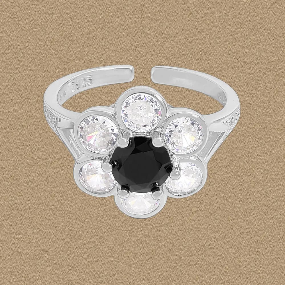 Flower-shaped ring with six clear stones around a central black gemstone in sterling silver.