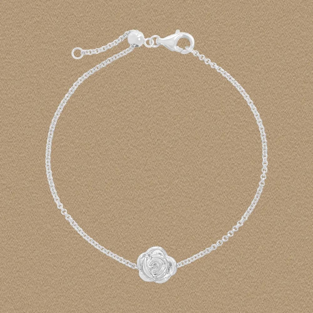 Delicate sterling silver bracelet with a central rose charm and a lobster clasp.