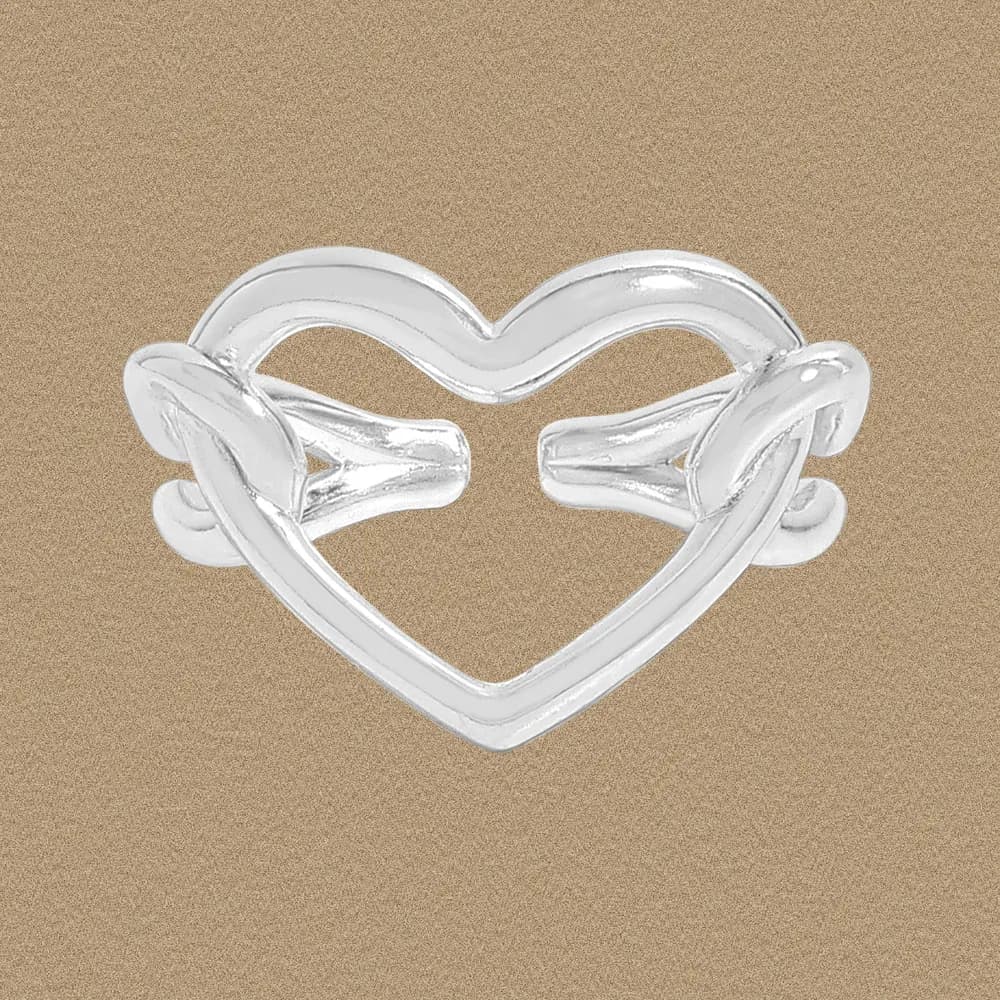 Polished sterling silver open heart ring displayed against a warm beige background.