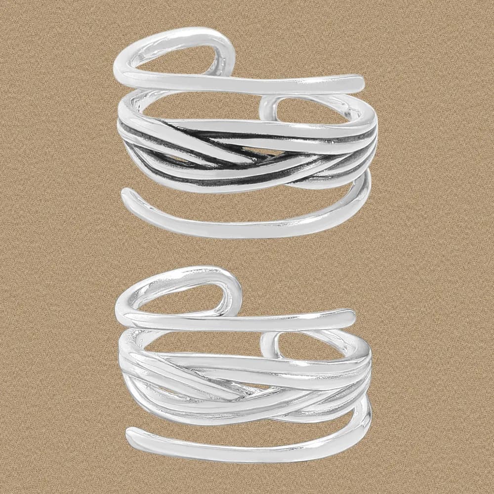 Close-up of a polished sterling silver twisted multi-band ring against a sandy backdrop.