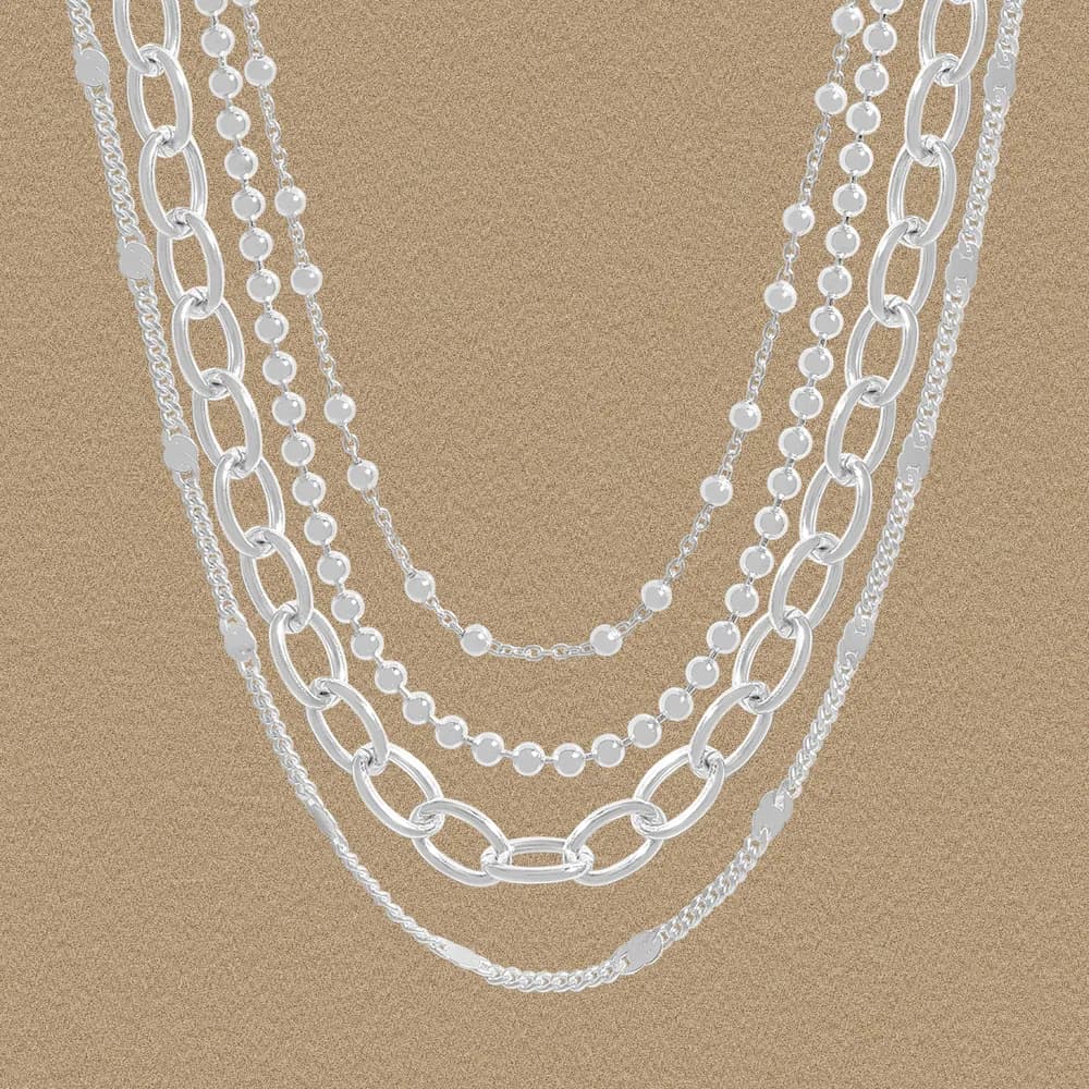 Multi-layered Sterling Silver Necklace with varying chain styles cascading together on a beige background.