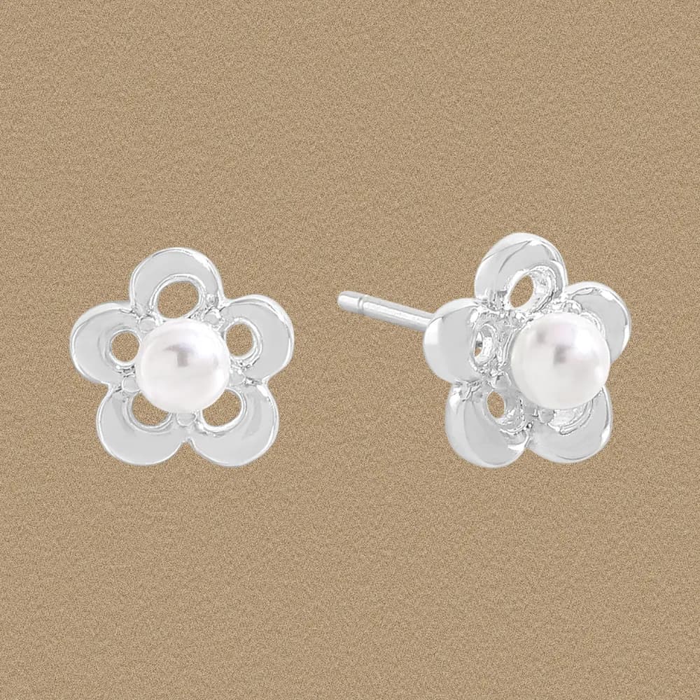 Polished sterling silver flower stud earrings with a central pearl on a warm beige background.