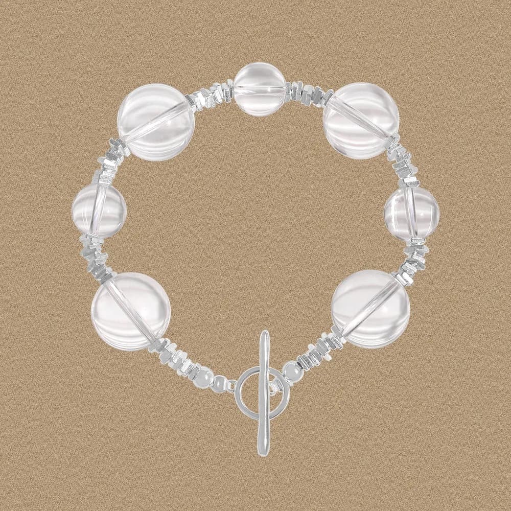 Polished sterling silver bracelet with large clear beads and a circular toggle clasp on a neutral background.