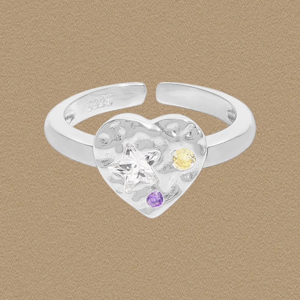 Polished silver heart ring with star-cut center stone and colorful accents on a neutral background.