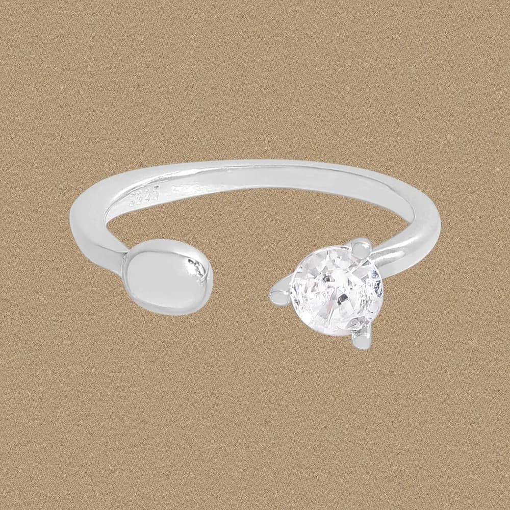 Polished sterling silver open-end ring with a round bead on one end and a clear faceted stone on the other.