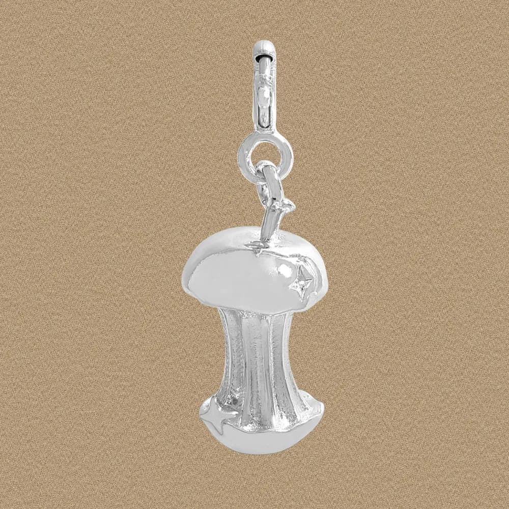 Polished sterling silver mushroom pendant with a circular jump ring on a beige background.